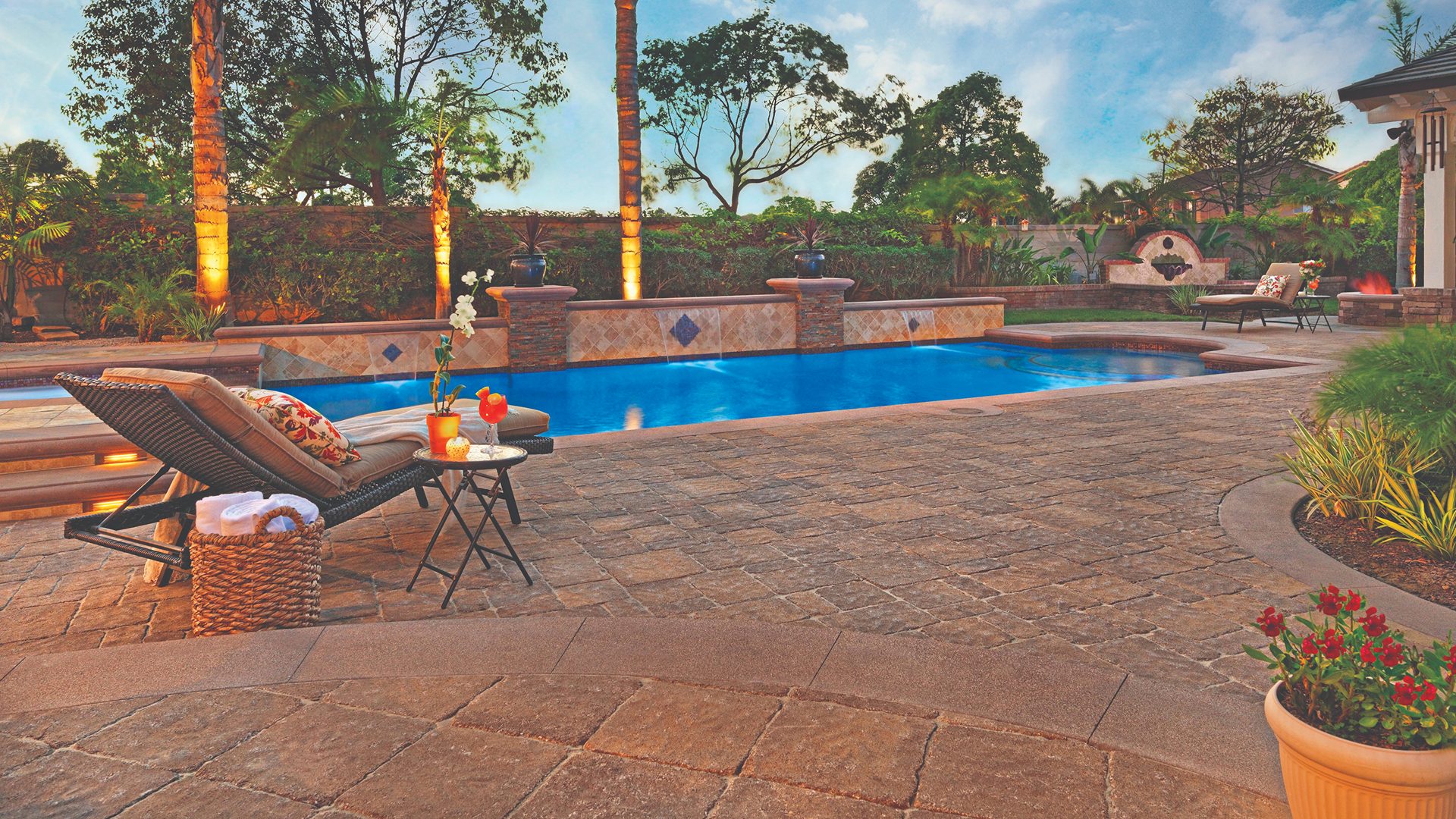 Estate cobble paver pool deck with lounge chairs at sunset